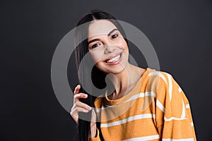 Portrait of happy young woman with beautiful black hair and charming smile on dark background