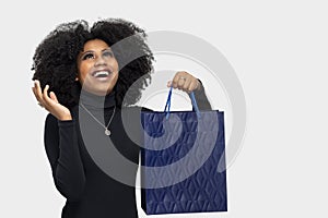 Portrait of a happy young woman with big smile looking up holding shopping bag isolated on gray background, end of year sale or mi photo