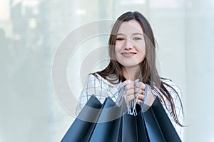 Portrait of happy young woman with black shopping bag. Sale. Close up