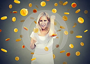 Portrait of a happy young woman celebrating financial success under a bitcoin rain