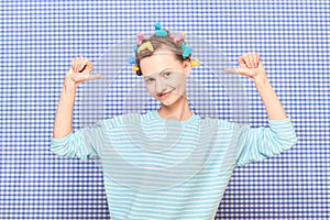 Portrait of happy young woman with colorful hair curlers on head