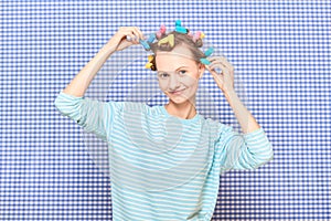 Portrait of happy young woman with colorful hair curlers on head