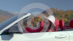 portrait of happy young woman in convertible car, weekend trip and rest in mountains, smiling lady