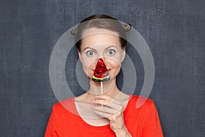 Portrait of happy young woman covering her face with lollipop
