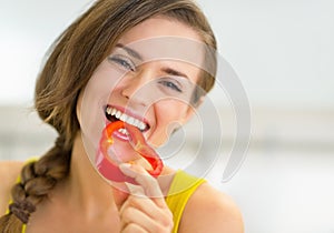 Portrait of happy young woman eating bell pepper