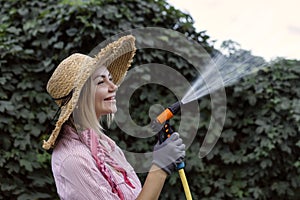 portrait of happy young woman gardener watering garden with hose. Hobby concept