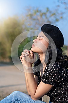 Portrait of happy young woman hands praying to god blessing to wish to have a better life outdoors with nature background