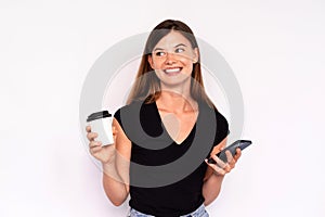 Portrait of happy young woman holding mobile phone and coffee