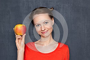 Portrait of happy young woman holding ripe yellow-red apple