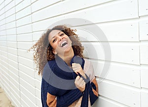 Portrait of a happy young woman holding sweater and laughing outdoors