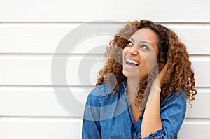 Portrait of a happy young woman laughing outdoors with hand in hair