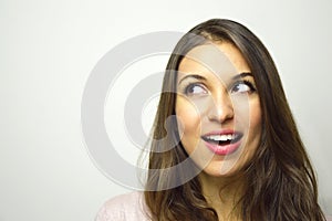 Portrait of happy young woman looking to the side with curiosity on white background. Copy space.