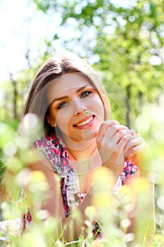 Portrait of happy young woman lying in a meadow on a warm summer