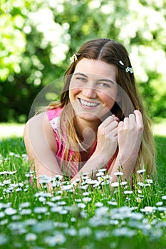 Portrait of a happy young woman lying outdoors on grass and flowers