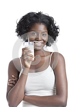 Portrait of happy young woman with milk moustache holding glass of milk