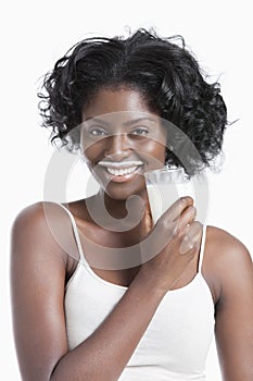 Portrait of happy young woman with milk moustache holding glass of milk