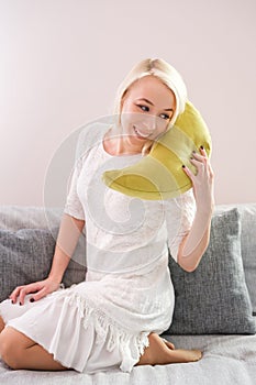 Portrait of happy young woman with mobile phone sitting on couch at home