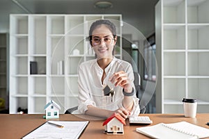 Portrait of happy young woman in modern flat house or apartment looking at camera holding bunch of keys