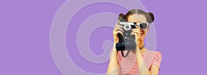Portrait of happy young woman photographer with film camera, female on violet studio background