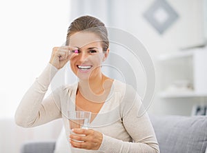 Portrait of happy young woman with pill and glass of water