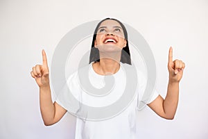 Portrait of happy young woman pointing fingers upwards