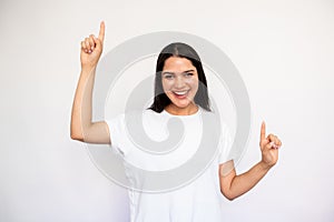 Portrait of happy young woman pointing forefingers upwards