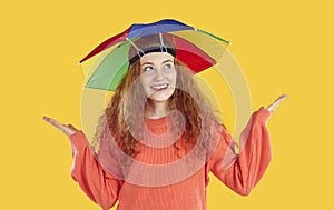 Portrait of happy young woman with rainbow hat umbrella on her head that protects from rain or sun.