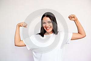 Portrait of happy young woman showing biceps on white background