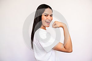 Portrait of happy young woman showing muscle on white background