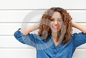 Portrait of a happy young woman smiling with hands in hair