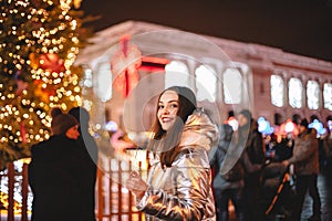 Portrait of happy young woman standing by Christmas tree