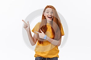 Portrait of happy young woman standing isolated over white wall background. Looking camera showing copyspace pointing