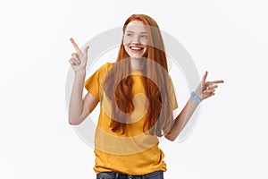 Portrait of happy young woman standing isolated over white wall background. Looking camera showing copyspace pointing