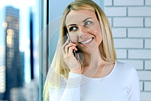 Portrait of happy young Woman Talking On Mobile Phone, standing near with window
