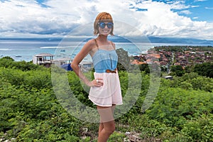 Portrait of happy young woman, tropical ocean view. Travel and Vacation. Outdoor shot. Nusa Lembongan, Bali, Indonesia.