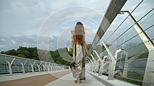 Portrait of happy young woman walking across the bridge in the city