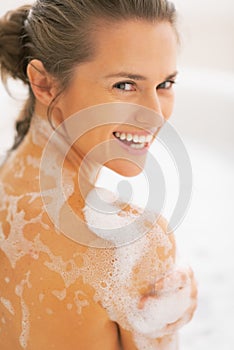 Portrait of happy young woman washing in bathtub