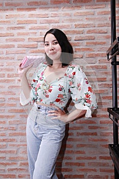 Portrait of a happy young woman Wearing a floral pattern shirt and a brick wall