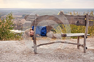 Portrait of happy young boy sitting on a wooden bench outdoors