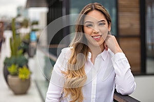 Portrait head shot of a young 20`s hispanic american female in the city, smiling with nice white teeth smile