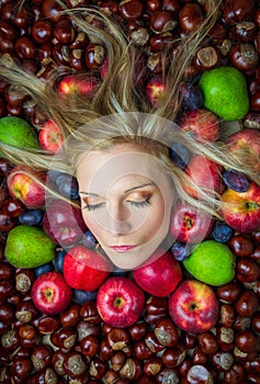 Portrait, head of young beauty caucasian woman with blonde hair and closed eye in fruit and chestnut background. Health eating,