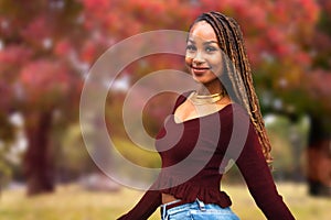 Portrait headshot of a beautiful commercial model african american woman, cheerful casual attire in park with autumn leaves