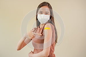 Portrait of health care asian young woman wearing face mask protect, getting vaccine of covid-19, influenza in casual, showing arm