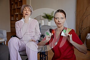 Portrait of healthcare worker holding pills and senior patient of nursing home