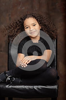 Portrait of  healthy attractive mixed race little girl with curly ringlets hairstyle and pretty face posing indoor looking at