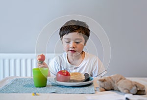 Portrait Healthy kid eating strawberries, apple and toast bread. Hungry little boy having breakfast at home., Child tasting fresh