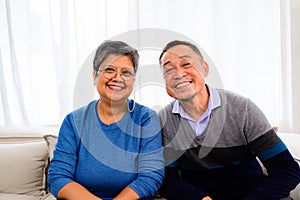 Portrait of healthy senior man and woman sitting on sofa at home, Happy senior married couple spending time in living