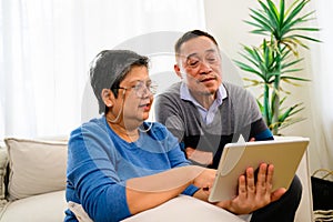 Portrait of healthy senior man and woman using laptop together on sofa at home, Happy senior married couple spending