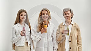 Portrait of healthy three generations of women drink juices