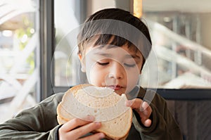 Portrait healthy young boy eating bacon sandwich, School Kid having breakfast in the cafe be for go to school, Child bitting toast
